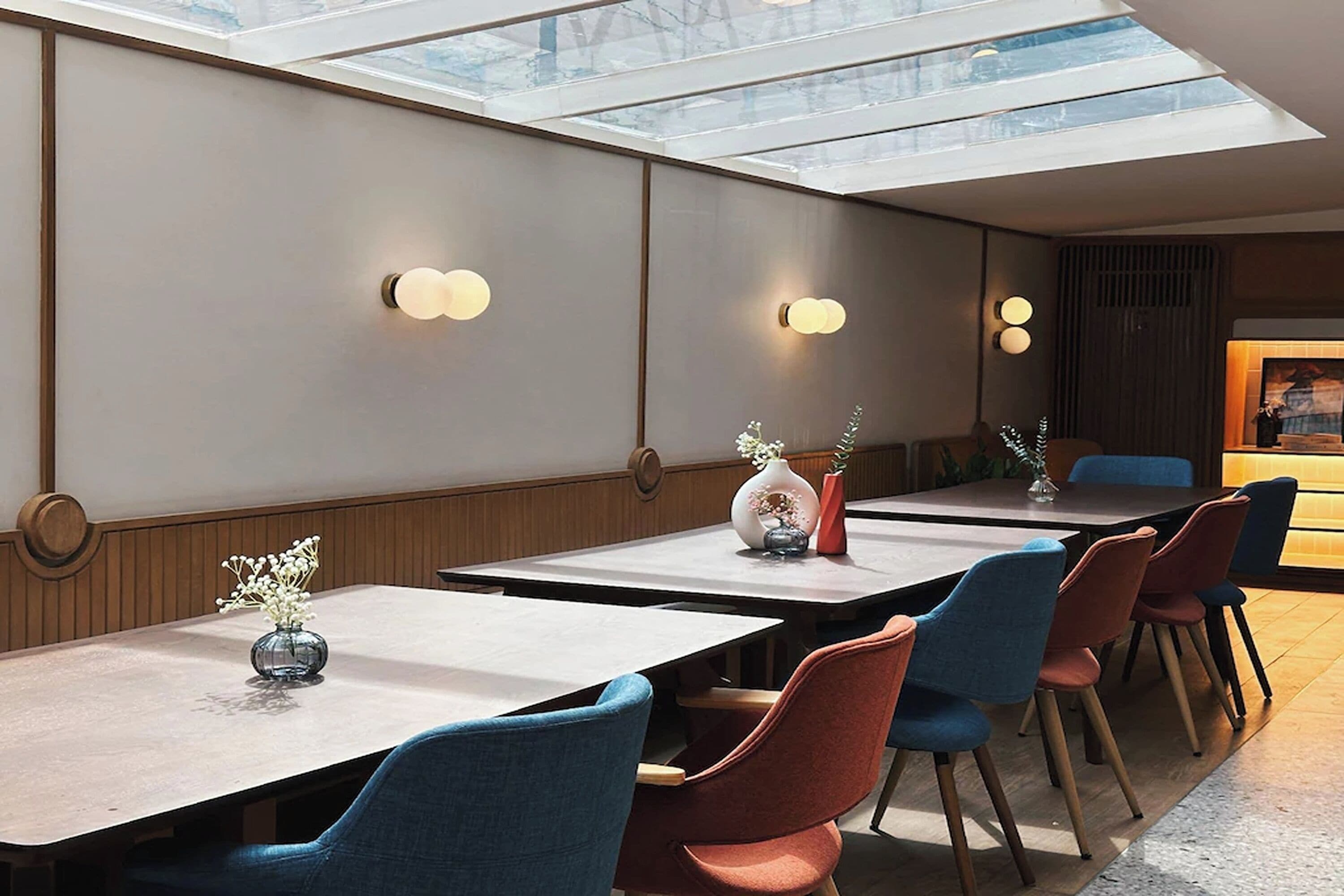 A modern dining area with long tables, comfortable chairs, and decorative vases.