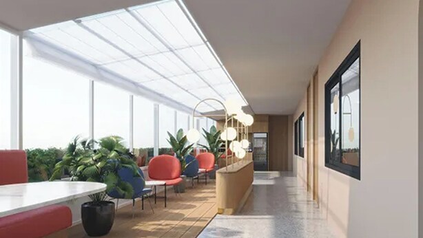 A modern indoor space with a long corridor, seating areas with red and blue chairs, potted plants, and a white reception desk. - Parcel Hotel Bangkok (Bangkok)
