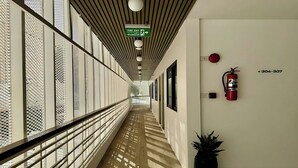 A corridor with a fire exit sign, a fire extinguisher, and a potted plant. - Parcel Hotel Bangkok (Bangkok)