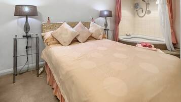Une chambre à coucher comprenant un lit, deux lampes de chevet, une table de chevet, une salle de bain avec une baignoire et une douche.