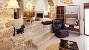 Un salon spacieux avec un mur en pierre, une cheminée, des meubles en cuir et une table basse en verre.