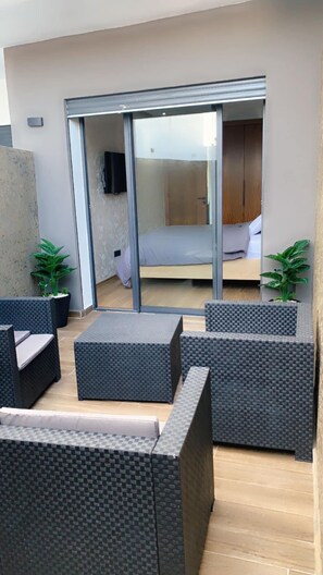 Relax in an outdoor lounge with a sofa, coffee table, and glass door leading to a bedroom.