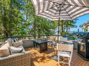 An outdoor deck with a grill, seating area, and a view of the ocean.