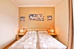 Una cama doble con colcha de lunares, dos lámparas de noche y tres cuadros colgados en la pared.