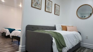 Une chambre d’hôtel avec un grand lit, un lit plus petit et un miroir au mur.