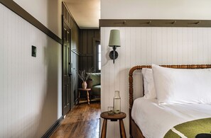 A bedroom with a wooden bed, a bedside table with a lamp, and a view into the hallway.