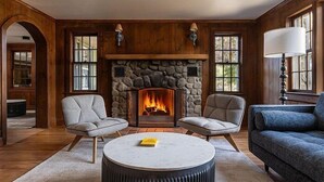 A cozy living room with a stone fireplace, two armchairs, a round coffee table, and a blue sofa. - Hemlock Neversink  (Neversink)