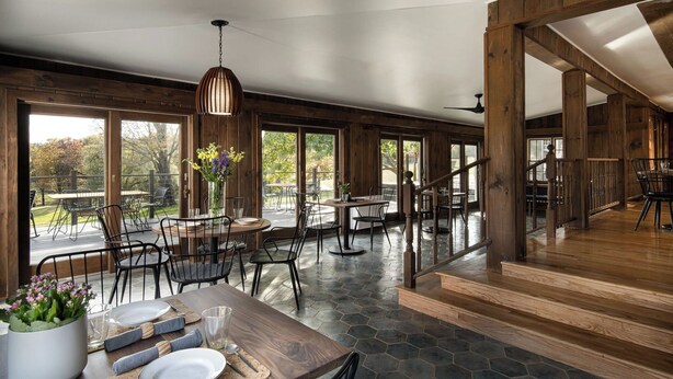 A spacious dining area with wooden floors, large windows, and a modern chandelier. - Hemlock Neversink  (Neversink)