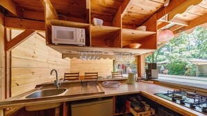 Une cuisine rustique, située dans une cabane en bois, équipée d’un évier, d’un four à micro-ondes et d’une cuisinière.