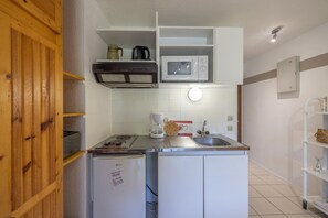 A compact kitchen with a microwave, coffee maker, and a refrigerator.