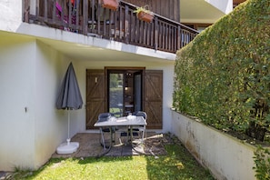 A patio with a table and chairs, a small umbrella, and a wooden fence.