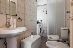 A bathroom with a sink, toilet, bidet, and washing machine. - City Cottage with Garden & Pool  (Catania)