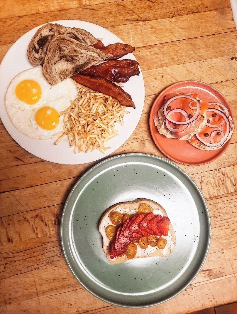 Ein Frühstücksteller mit Eiern, Speck, Bratkartoffeln und ein Teller Räucherlachs mit Zwiebeln.