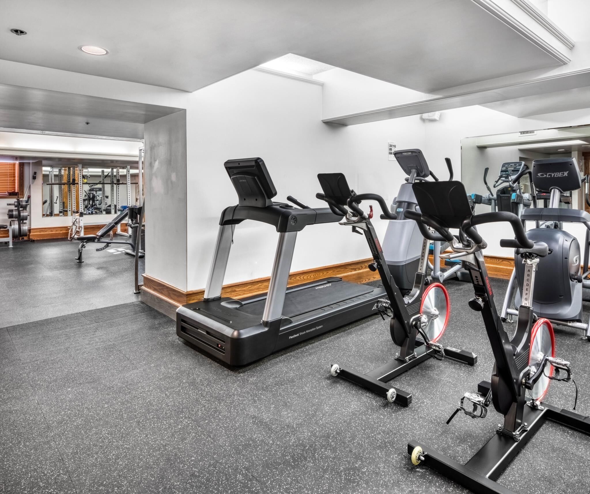 Un gimnasio con cintas de correr, bicicletas estáticas y máquinas de pesas.
