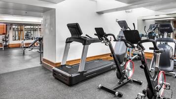 Un gimnasio con cintas de correr, bicicletas estáticas y máquinas de pesas.