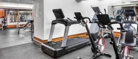 Un gimnasio con cintas de correr, bicicletas estáticas y máquinas de pesas.