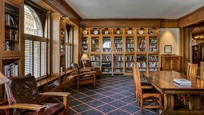A library with wooden bookshelves, a large table, and leather chairs. - Alta Club (Salt Lake City)