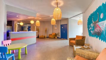 A lobby with wicker furniture, a reception desk, and hanging lights.