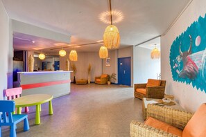 A lobby with wicker furniture, a reception desk, and hanging lights.