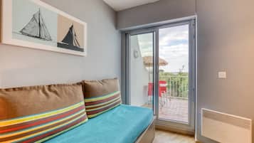 Una habitación con una cama, una puerta corrediza de vidrio que da a un espacio exterior y un cuadro en la pared.