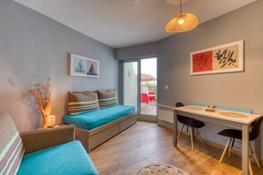 Una habitación moderna con sofá, una mesa de comedor con sillas, una ventana y obras de arte en las paredes.