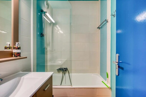 A bathroom with a bathtub, a shower, a sink, and a mirror.