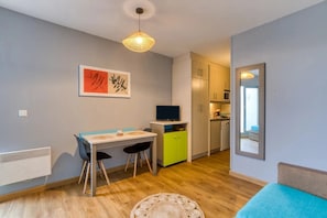 A compact living space with a dining area, kitchenette, and a mirror reflecting the room.