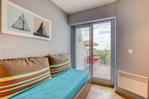 Una habitación con cama, puerta corrediza de vidrio que da a un espacio exterior y un cuadro en la pared.
