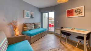 Ein modernes Zimmer mit einer Couch, einem Esstisch mit Stühlen, einem Fenster und Bildern an den Wänden.