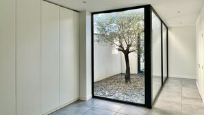 A modern interior with a glass partition, a tree outside, and a tiled floor. - Magnificent contemporary architect-designed villa  (Mérignac)