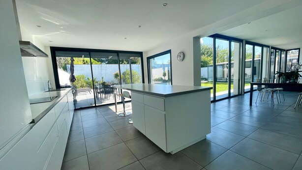 A modern kitchen with a central island, large windows, and a view of the outdoors. - Magnificent contemporary architect-designed villa  (Mérignac)