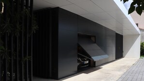 A modern building with a sleek design, featuring a car parked under a covered area. - Magnificent contemporary architect-designed villa  (Mérignac)