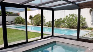 A modern indoor swimming pool with clear glass walls, a separate section for lap swimming, and a view of the backyard. - Magnificent contemporary architect-designed villa  (Mérignac)