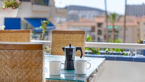 A balcony with wicker chairs, a glass table, a coffee maker, and two white mugs. - ‘Graciosa’ Holiday Apartment with Sea Views, Private Terrace & Wi-Fi (Arona)