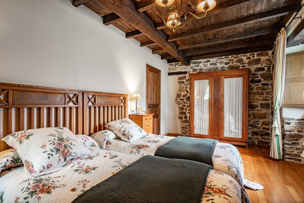 Un dormitorio con cabecera de madera, pared de piedra y armario de madera.