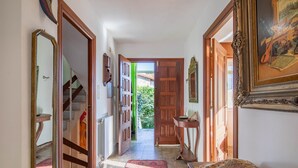 A hallway with a wooden door, a mirror, a framed picture, and a patterned rug. - Holiday Home 'O Axouxere' with Mountain View, Private Terrace and Wi-Fi (Feira do Tres)
