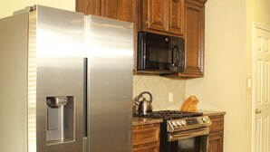 Une cuisine équipée d’appareils électroménagers en acier inoxydable, de meubles de rangement en bois, d’un four à micro-ondes et d’une cuisinière.