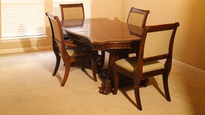 Une salle à manger avec un lustre, une table en bois et quatre chaises.