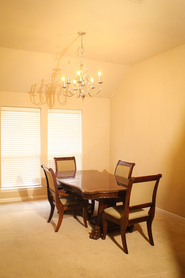 Comedor con candelabro, mesa de madera y cuatro sillas.