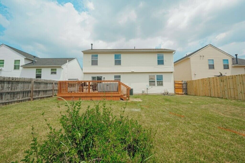 A two-story house with a wooden deck in the backyard.