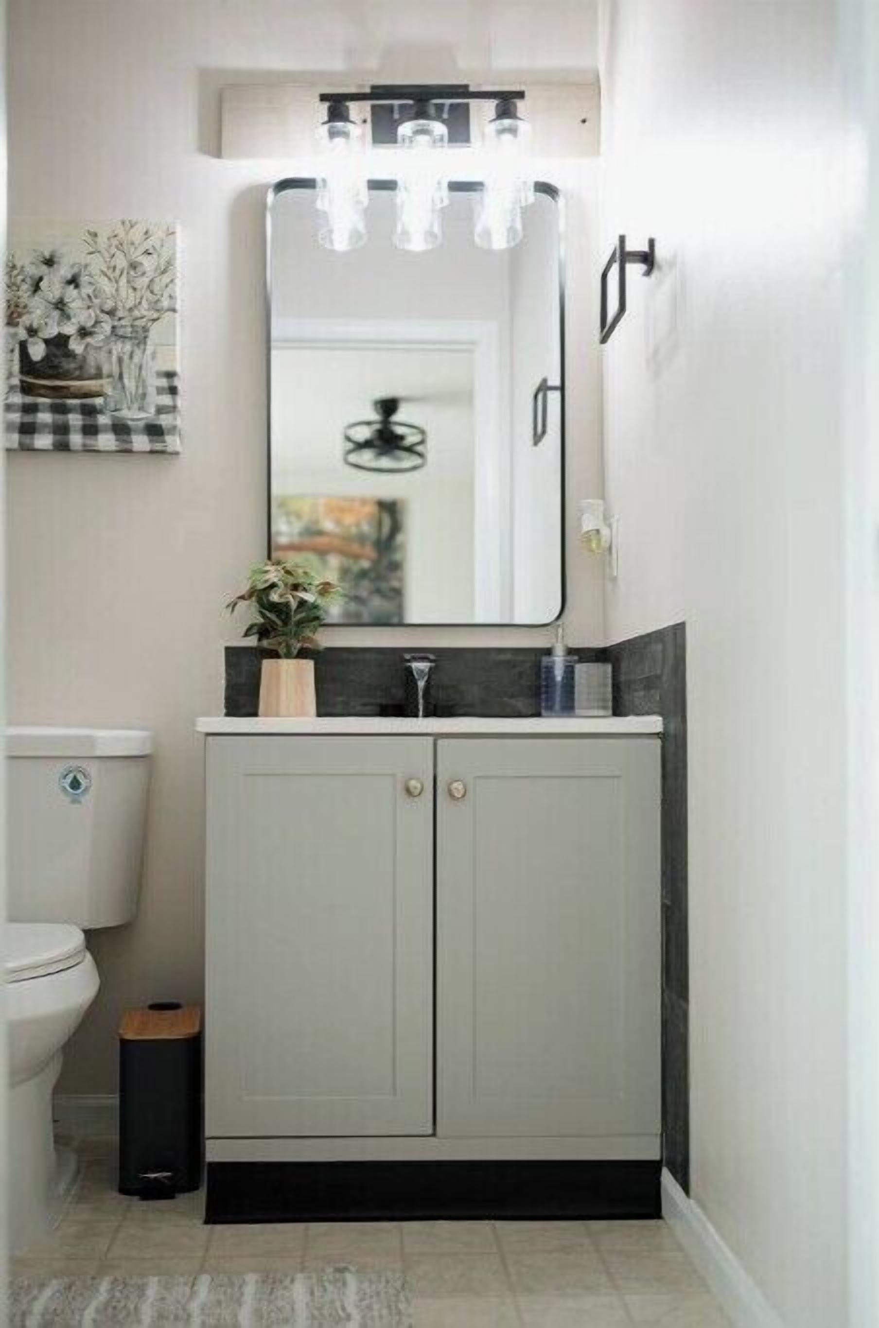 A bathroom with a grey cabinet, a white toilet, and a mirror above the sink.