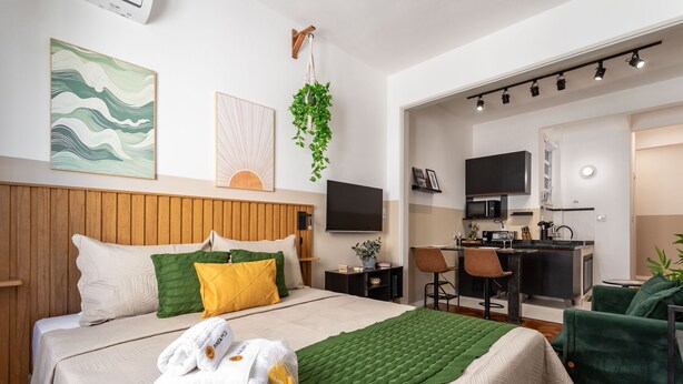 Ein Hotelzimmer mit Bett, Schreibtisch, Stuhl, Fernseher und einer Küchenzeile.