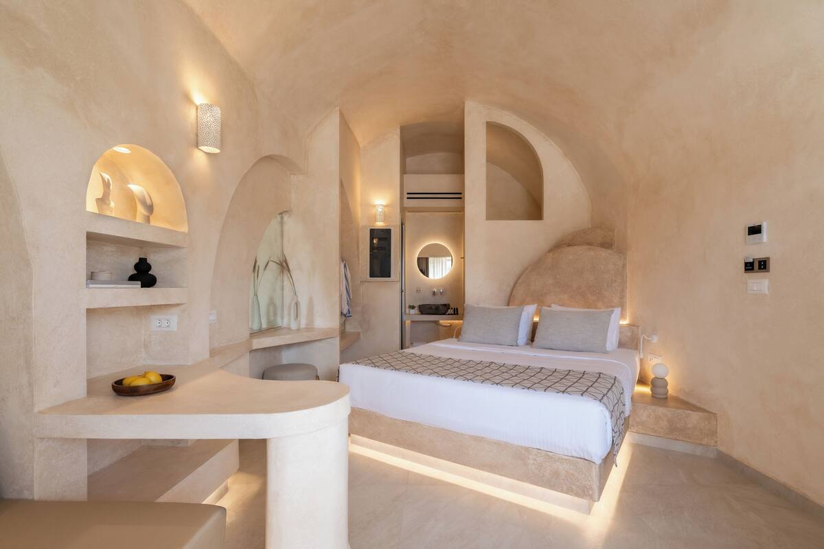 A bedroom with a bed, bedside table, and a built-in shelf with decorative items.