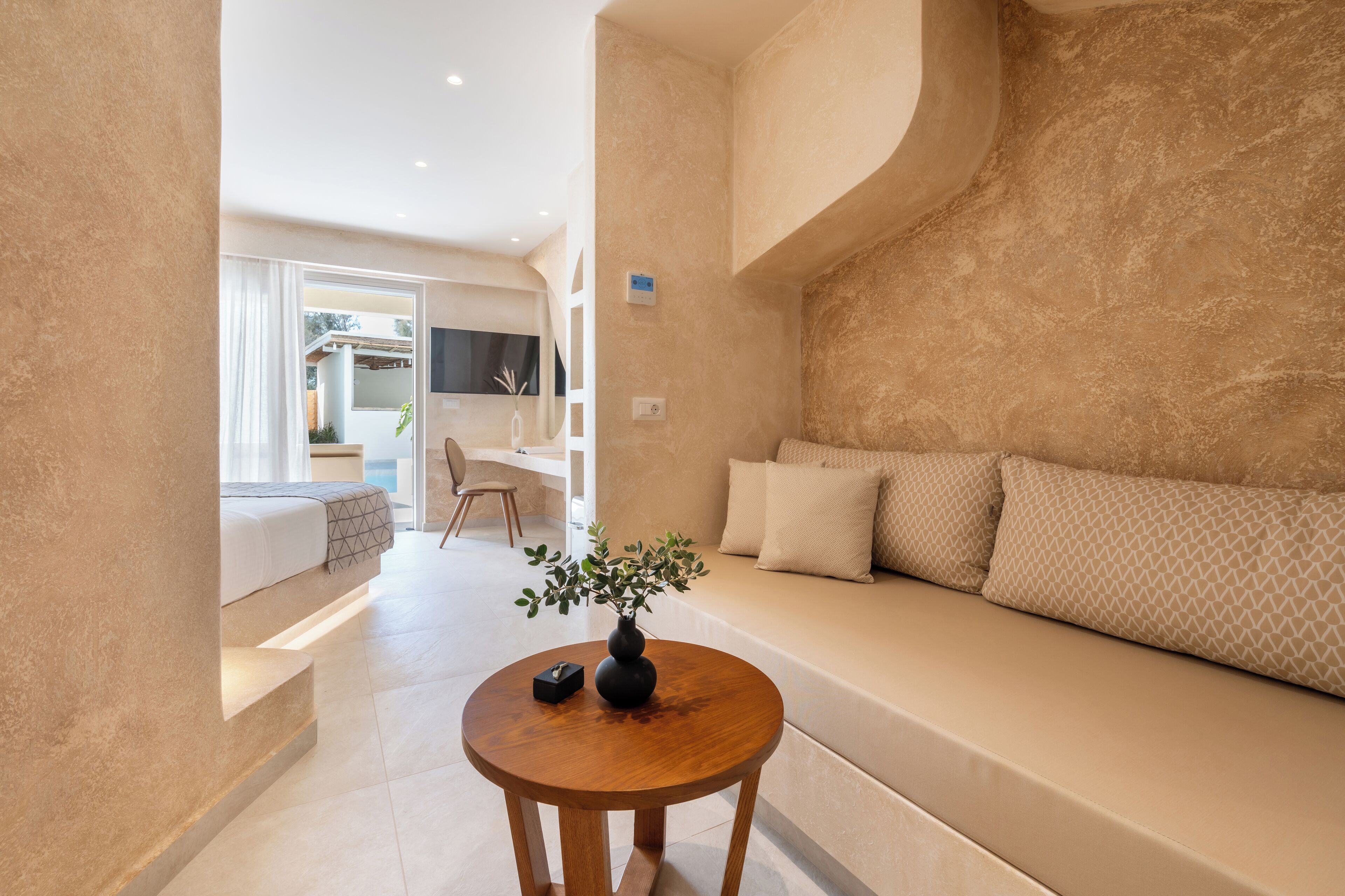 Een moderne woonkamer met een bank, een ronde houten tafel met een vaas, en uitzicht op het buiten.