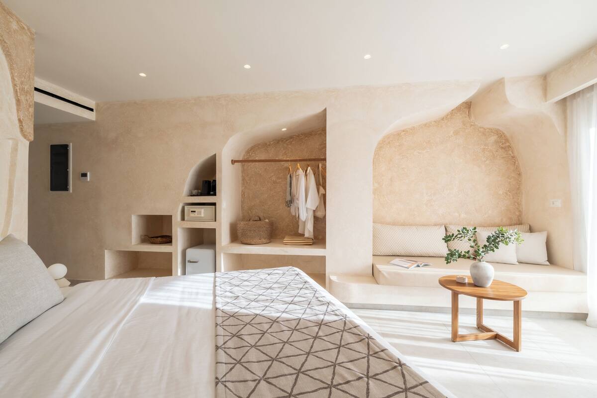 A modern bedroom with a large bed, a bedside table with a vase, and a built-in wardrobe.