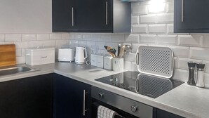 A modern kitchen with dark cabinets, a stainless steel countertop, a built-in toaster, a coffee maker, and a kettle. - Welcome to Clementi, your modern holiday retreat in Penrith, Cumbria. (Penrith)