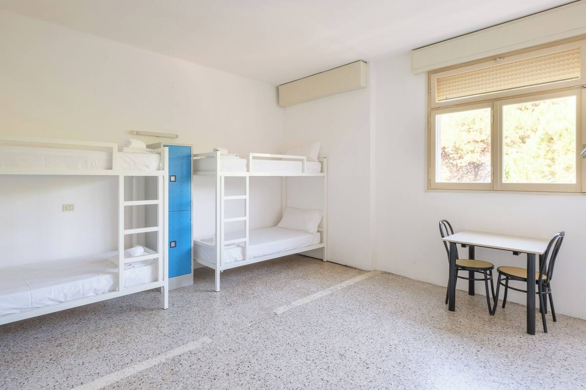 A room with bunk beds, a desk, and two chairs.