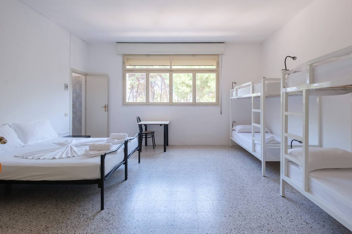 A room with bunk beds, a desk, and a chair.