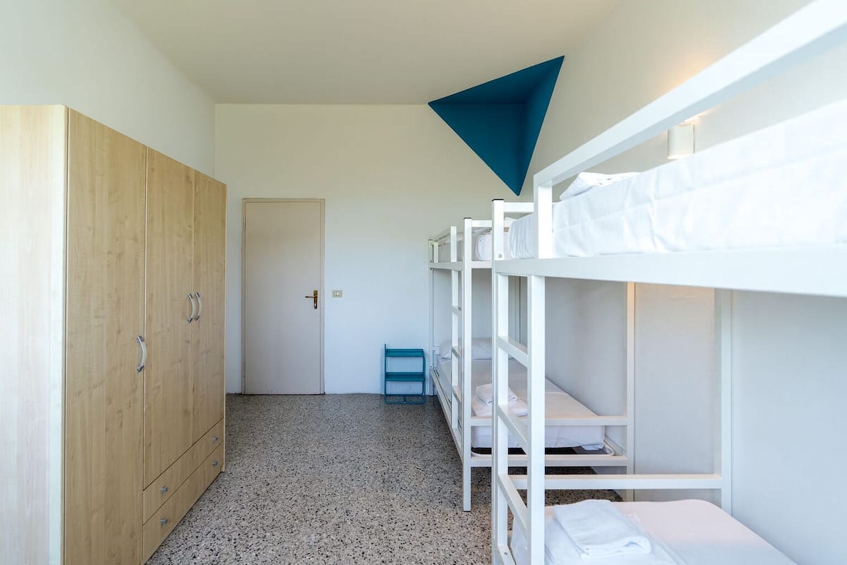 A room with bunk beds, a wooden wardrobe, and a door.