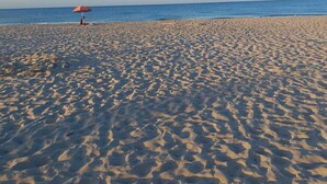 A beach with a single umbrella and a person standing under it. - Meet Hostel Cervia (Cervia)